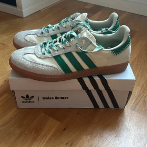 Adidas x Wales Bonner Samba sneakers - Säljer ett par Adidas x Wales Bonner Samba sneakers i vitt och grönt med klassiska tre ränder på sidan. Skorna har gröna och vita snören, mockadetaljer framtill och gummisula. Kommer med originalkartong. 