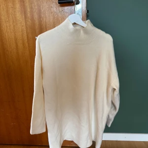 Vit polotröja från Zara - Säljer en klassisk vit polotröja från Zara. Tröjan är stickad med lång ärm och har en hög, ribbad krage. Perfekt att styla till olika outfits och passar bra under kyligare dagar.