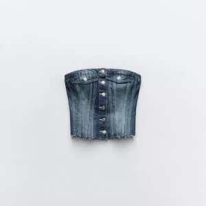 Jeans korsettopp från Zara - Säljer en snygg jeans korsettopp från Zara i blå denim. Toppen har knappar framtill och dekorativa fickor. Lappen bortklippt, men helt oanvänd.