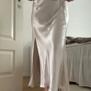 Satinkjol  - Säljer denna superfina silvriga satinkjol från Weekday. Storlek 34, resor i midjan så den är stretchig. En slit framtill.