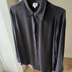 Svart skjorta från Twist & Tango - Stilren svart skjorta från Twist & Tango i storlek XS. Skjortan har klassisk krage, knäppning framtill och långa ärmar. Perfekt för en clean och enkel look. Materialet känns mjukt och har ett snyggt fall.