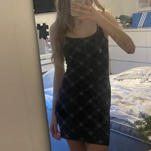 Svart och vit rutig klänning från Divided - Snygg svart klänning med vitt rutmönster från H&M. Klänningen har en stilren design med smala axelband och är oanvänd. Den är tillverkad i ett mjukt och bekvämt material med två lager💕