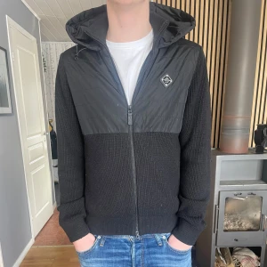 J lindeberg cardigan OG badge - Svart cardigan från J lindeberg i storlek M. Jackan säljs inte längre och har den snygga badgen på bröstet. Skicket är 10/10 bara att den behöver noppras lite. Skriv om ni har frågor eller funderingar.