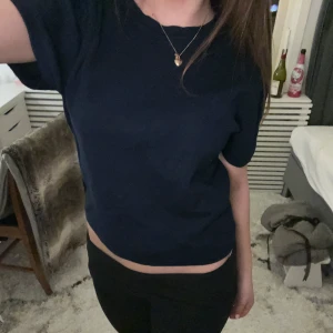 Mörkblå topp från Gina Tricot - Säljer en stilren mörkblå topp från Gina Tricot. Toppen har korta ärmar och en enkel design som passar perfekt till vardags. Den är tillverkad i ett mjukt material som känns skönt mot huden. Jag vill bara komentera att storleken är xl men jag har ingen aning om varför då jag tycker den passar som xs då de e vad jag brukar ha o tröjan passar väldigt bra