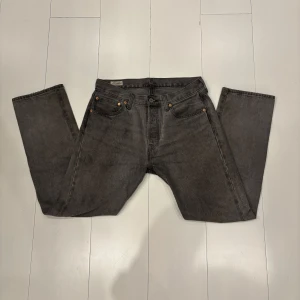 Grå Levis 501 jeans - Säljer ett par klassiska grå Levis 501 jeans. De har en straight passform och är tillverkade i slitstarkt denim. Perfekta för en avslappnad stil med fem fickor och knappgylf.