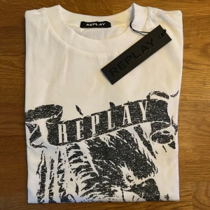 Replay T-shirt - Fet replay tshirt med ett snyggt tryck på framsidan. Tröjan är aldrig använd och lappen sitter kvar. Tröjan kostar ca 1500kr nypris.                                                                                             Priset är ej hugget i sten!