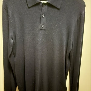 Svart långärmad pikétröja från Only & Sons - Snygg svart långärmad pikétröja från Only & Sons. Tröjan har en klassisk krage med tre knappar framtill. Perfekt för en stilren look.