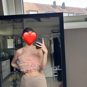 Rosa volang tubtopp - Säljer en söt rosa tubtopp med volangdetaljer. Perfekt för sommarens varma dagar. Toppen är ärmlös och har en fluffig design som ger en lekfull/festlig look.