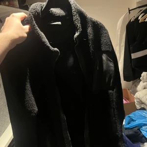 Svart teddyjacka från belstaff - Mysig svart teddyjacka med långärmad design. Perfekt för kyliga dagar med sitt mjuka och fluffiga material. Jackan har en stilren look och är lätt att matcha med olika outfits.