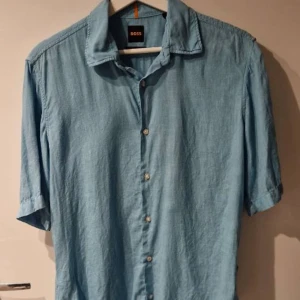Blå linneskjorta från Boss - Säljer en snygg blå skjorta från Boss i linne med korta ärmar. Använd 1 gång. Size = S.  