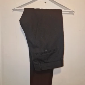 Svarta kostymbyxor från Tiger of Sweden  - Snygga svarta kostymbyxor med en klassisk design. Perfekta för en stilren look.