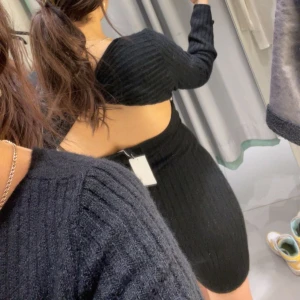 Svart ribbad klänning - Snygg svart ribbad klänning med öppen rygg och långärmad design. Perfekt för en stilren look.