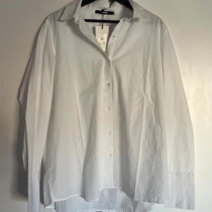 Vit skjorta från Bik Bok - Säljer en stilren vit skjorta från Bik Bok i storlek L. Skjortan har en klassisk design med knappar framtill och långa ärmar.