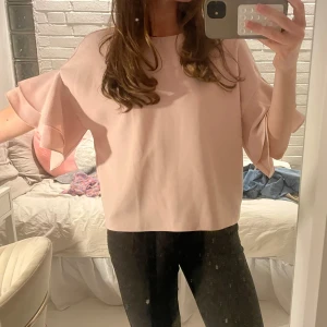 Rosa blus med volangärmar - Säljer en söt rosa blus med volangärmar. Blusen har en lös passform och är perfekt för en stilren look. Köpt second hand, sömmarna är lite uppslitna i kragen, kan skicka bild på de 🩷🩷🩷storlek står inte men skulle säga runt S