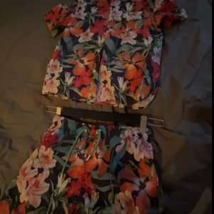 Blommiga shorts från Gant - Snygga blommiga badbyxor från Gant med ett färgglatt mönster i orange, röd och grönt. Perfekta för sommarens äventyr. Shortsen har en bekväm passform och snörning i midjan för justerbarhet.