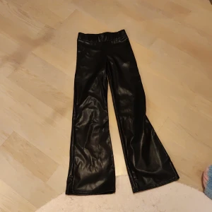 Svarta byxor från H&M - Snygga svarta byxor i syntetmaterial från H&M. De har en elastisk midja och en rak passform som ger en stilren look. Perfekta för en trendig outfit.