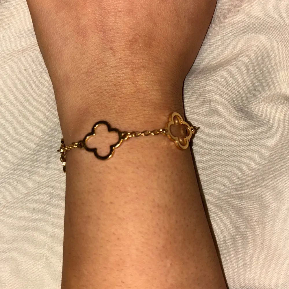Elegant guldarmband med flera fyrklöverformade länkar. Armbandet har en tunn kedja som binder samman de stilrena klövermotiven. Perfekt för att ge en touch av lyx till din outfit. Aldrig använd innan.. Asusteet.