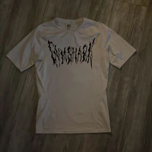 Vit t-shirt från Gymshark - Säljer en vit comprassion t-shirt från Gymshark med ett coolt tryck i svart på framsidan. Perfekt för träning eller en avslappnad stil. T-shirten har korta ärmar och är tillverkad i ett bekvämt material.