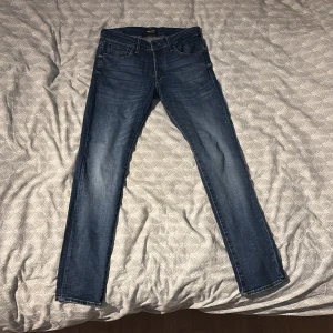 Blå jeans jack and jones Slim/Glenn  - Snygga blå jeans med slim passform. De har en klassisk design med fem fickor och dragkedja. Perfekta för en stilren look.