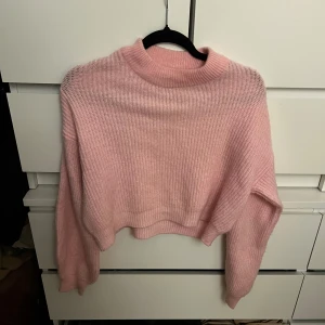 Rosa stickad tröja från NLY Trend - Säljer en söt rosa stickad tröja från NLY Trend. Tröjan är croppad med långa ärmar och har en ribbad design. Perfekt för en mysig och stilren look. 💖