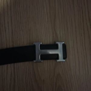 H3rmes bälte - Snyggt svart bälte med ett stilrent H-format spänne i silver. Perfekt för att ge en elegant touch till din outfit. Tillverkat i skinn för en klassisk look.
