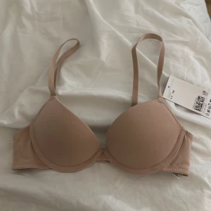 Beige BH från H&M - Säljer en beige BH från H&M i storlek 70B. Den har justerbara axelband och en slät design som ger en bekväm passform. Perfekt för dagligt bruk. Nypris 300kr