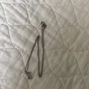 Silverfärgat armband med hjärtdetalj - Elegant silverfärgat halsband med en fin hjärtdetalj. Kedjan är tunn och smidig, vilket gör den bekväm att bära hela dagen.