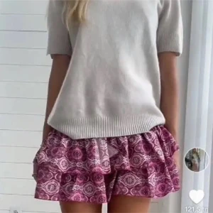 Mönstrad rosa kortkjol meet me there  - Säljer en söt rosa kortkjol med ett unikt mönster. Kjolen har volanger som ger en lekfull look och en elastisk midja för bekväm passform. Perfekt för varma dagar!