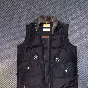 Parajumper väst - Säljer en svart väst ifrån parajumper i perfekt skick, använd en vinter sedan har den legat i garderoben, Västen är storlek L och passar dig året runt. Priset kan diskuteras vid en snabb affär