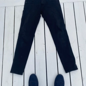 Svarta Replay Anbass jeans slim fit - Svarta jeans från Replay, modell Anbass. Slim fit 32x32 med klassisk femficksdesign, svarta sömmar och Replay-logga på fickan. Jeansen har normal midja och är tillverkade i mjukt bomullsmaterial med lite stretch för extra komfort.