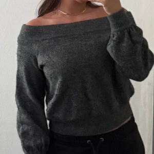 Stickad mörkgrå offshoulder tröja  - Supermjuk mörkgrå stickad tröja från Hm med bred offshoulder-ringning och långa ärmar. Ribbstickade muddar. Storlek S. 