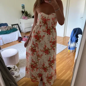 Vit blommig axelbandslös maxiklänning - Superfin axelbandslös långklänning i vitt med blommigt mönster i rosa och grönt. 