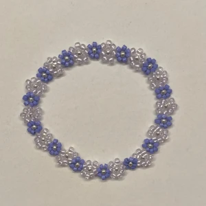 Pärlarmband med lila blommor - Hemgjort armband gjort av små ljuslila och lila blommor med en silverfärgad pärla i mitten. Gjort med en elastisk tråd, och kan såklart göras i andra storlekar och färger💓                     Obs! -silverpärlorna kan tappa sin färg om de tvättas mycket i vatten.