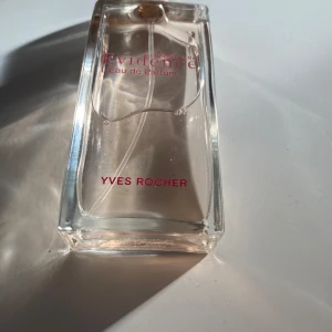 Comme une Evidence parfym Yves Rocher - Comme une Evidence Eau de Parfum från Yves Rocher. Flaskan är rektangulär och genomskinlig med rosa text och har en stilren, minimalistisk design. Parfymen har en transparent vätska och flaskan är tillverkad i glas med en plastkork.