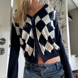 Mörkblå rutig kofta från Brandy Melville - Snygg mörkblå kofta från Brandy Melville med vita rutiga detaljer framtill. Koftan har v-ringning, knappar hela vägen och långa ärmar. 