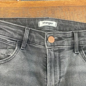 Gråa bootcut jeans från Wrangler - Snygga gråa jeans från Wrangler. Mid-waist och är tillverkad i stretchig denim för en bekväm känsla. Väl använda men inte mycket tecken på användning.❤️passade mig som 167-170❤️
