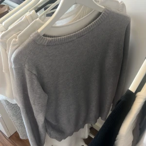 Grå stickad tröja från Vila - En enkel och stilren grå stickad tröja från Vila i storlek M. Tröjan har rund halsringning, ribbade muddar och lång ärm. Perfekt för lager-på-lager och passar till både jeans och kjol.