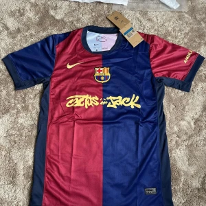 FC Barcelona x Cactus Jack Nike tröja - Snygg FC Barcelona fotbollströja i samarbete med Cactus Jack. Tröjan är kortärmad och har klassisk halva-halva design i vinröd och marinblå med gula detaljer och tryck. Tillverkad i lätt och ventilerande Dri-FIT-material. Perfekt för dig som älskar Barca och streetstyle.