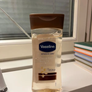 Vaseline Cocoa Radiant Body Oil 200ml - Vaseline Intensive Care Cocoa Radiant Body Oil med ren kakaosmör och vårdande oljor. Oljan är genomskinlig och kommer i en plastflaska med brunt lock. Perfekt för att ge huden en glow och mjuk känsla. Innehåller 200 ml.