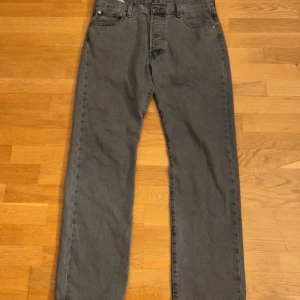 Grå Levi's 501 jeans W34 L32 - Säljer ett par klassiska grå Levi's 501 jeans med raka ben och normal passform. Jeansen har fem fickor, knappgylf och är tillverkade i slitstarkt denim. Perfekta för dig som gillar en tidlös och avslappnad stil.