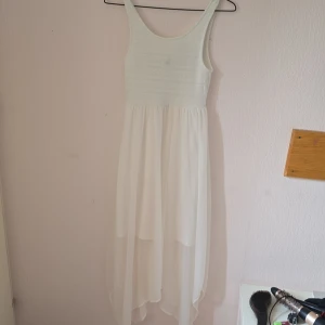 Vit långklänning från H&M Divided - Superfin vit långklänning från H&M Divided i storlek 36. Klänningen har ärmlös design, stretchig överdel med diskret spetsstruktur och ett luftigt, dubbellager kjolparti i chiffongliknande material. Perfekt för sommarens alla tillfällen!