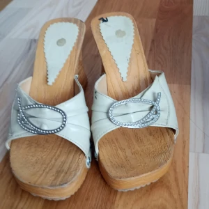 Beiga sandaler med platå och strass - Snygga beiga sandaler med breda remmar i skinnimitation och dekorativa spännen med strass. Skorna har en hög platåsula i trälook och öppen tå, perfekt för dig som gillar att sticka ut till ett party med detaljer.jag tror storleken är 37 eller 39 jag vet inte.Jag kommer dkriva att storleken är 37