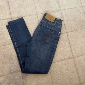 Tiger of sweden jeans  - Snygga blå tiger of sweden  jeans med klassisk femficksdesign och raka ben. Jeansen har en mellanblå tvätt och subtila slitningar för en avslappnad look. Tillverkade i mjukt bomullsjeans med en liten stretch för extra komfort.