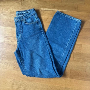Blå jeans från Bikbok - Klassiska blå jeans med rak passform och medelhög midja från Bikbok. Jeansen har fem fickor, knappgylf och är tillverkade i slitstarkt bomullsjeans. Perfekta för dig som gillar en tidlös och avslappnad look.