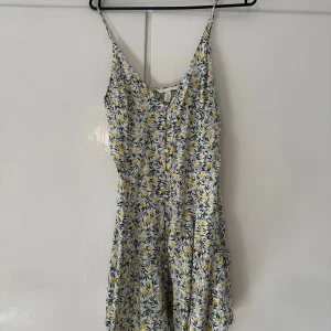 Blommig sommarklänning från H&M - Supersöt kort klänning från H&M med smala axelband och blommigt mönster i gult, grönt och vitt. Lätt och luftig, perfekt för varma dagar. Sitter snyggt med v-ringning och flowig kjol. En riktig sommarfavorit!