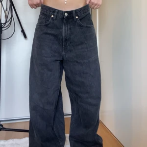 Svarta wide jeans med hög midja - Säljer ett par svarta jeans med riktigt breda ben och hög midja. Jeansen har klassiska fem fickor, bälteshällor och stängs med knapp och dragkedja. Materialet är kraftigt denim och passformen är loose och oversized för en chill vibe.