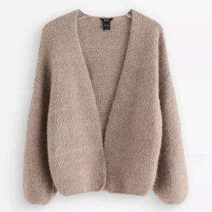 Beige stickad kofta från Lindex - Säljer nu min Lindex kofta som varit väldigt viral det senaste året! Koftan har långa ärmar och är tillverkad i ett mjukt, fluffigt material som känns lyxigt och varmt. Perfekt att slänga på sig när det är kyligt ute. Aldrig använd, nypris 399