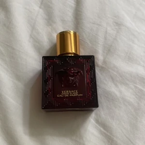 Versace Eros Flame Eau de Parfum - Versace Eros Flame Eau de Parfum i en lyxig, fyrkantig röd glasflaska med guldigt lock. Flaskan har en elegant Medusa-detalj och geometriskt mönster runt kanterna. Perfekt för dig som gillar exklusiva och intensiva dofter. Ca 20ml kvar! 