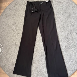 Svarta kostymbyxor med raka ben från H&M - Snygga svarta lågmidjade kostymbyxor med klassisk rak passform från H&M. Byxorna har diskret knapp- och dragkedjestängning. Användes ett antal gånger, men är i mycket bra skick. Pris kan diskuteras. 