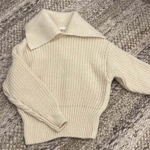 Beige stickad tröja med krage H&M - Säljer en chunky stickad tröja från H&M i beige/vit med bred krage och ribbade muddar. Långärmad. Storlek XS